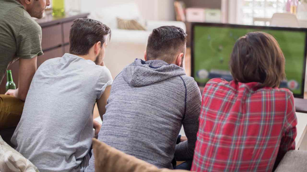 Un gruppo di amici guarda una partita di calcio in tv
